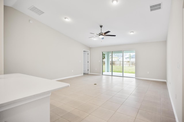 tiled empty room with ceiling fan and vaulted ceiling