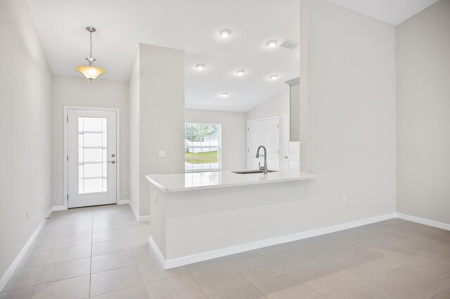 kitchen with lofted ceiling, sink, decorative light fixtures, light tile patterned floors, and kitchen peninsula