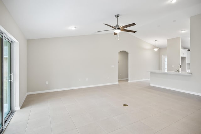 unfurnished living room featuring ceiling fan, sink, and vaulted ceiling