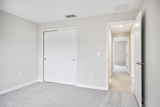 unfurnished bedroom featuring a closet and light carpet