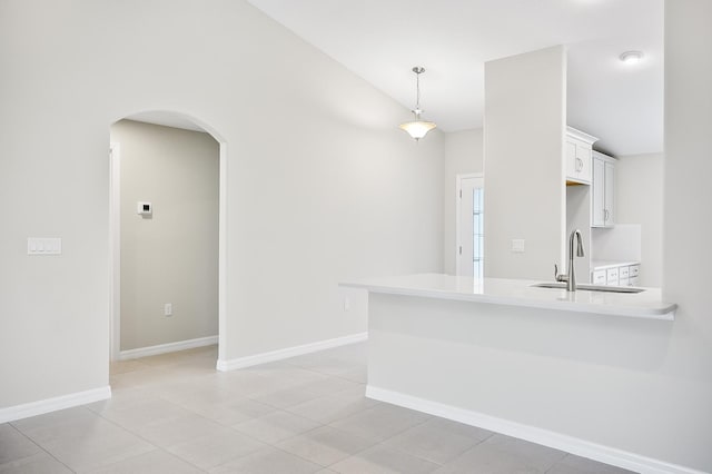 kitchen with light tile patterned flooring, sink, decorative light fixtures, kitchen peninsula, and white cabinets