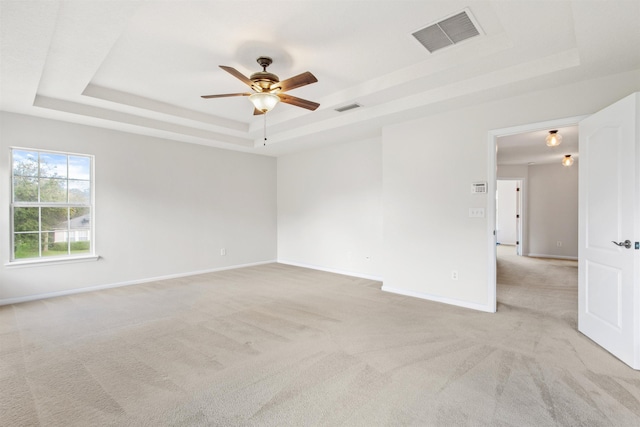 spare room featuring a tray ceiling, ceiling fan, and light colored carpet