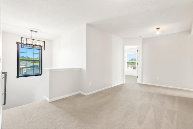 empty room featuring light carpet and a chandelier