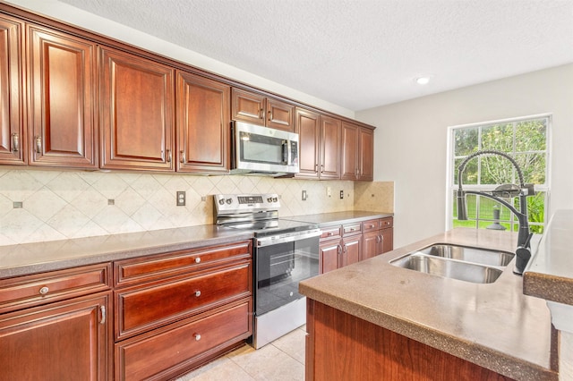 kitchen featuring appliances with stainless steel finishes, tasteful backsplash, a textured ceiling, sink, and light tile patterned floors