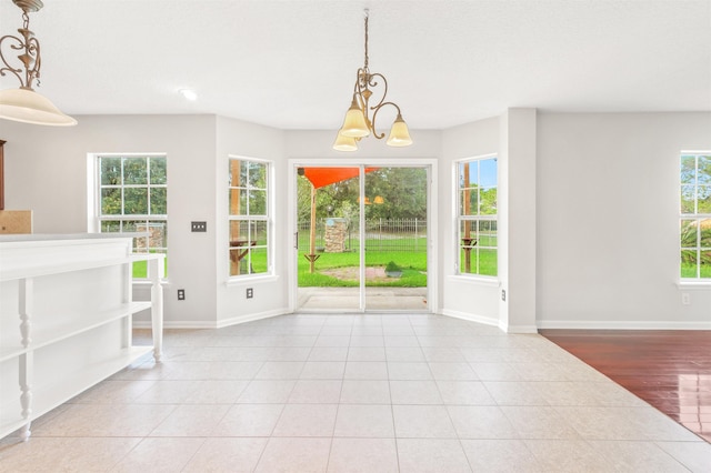 unfurnished dining area featuring plenty of natural light, light tile patterned floors, and a chandelier