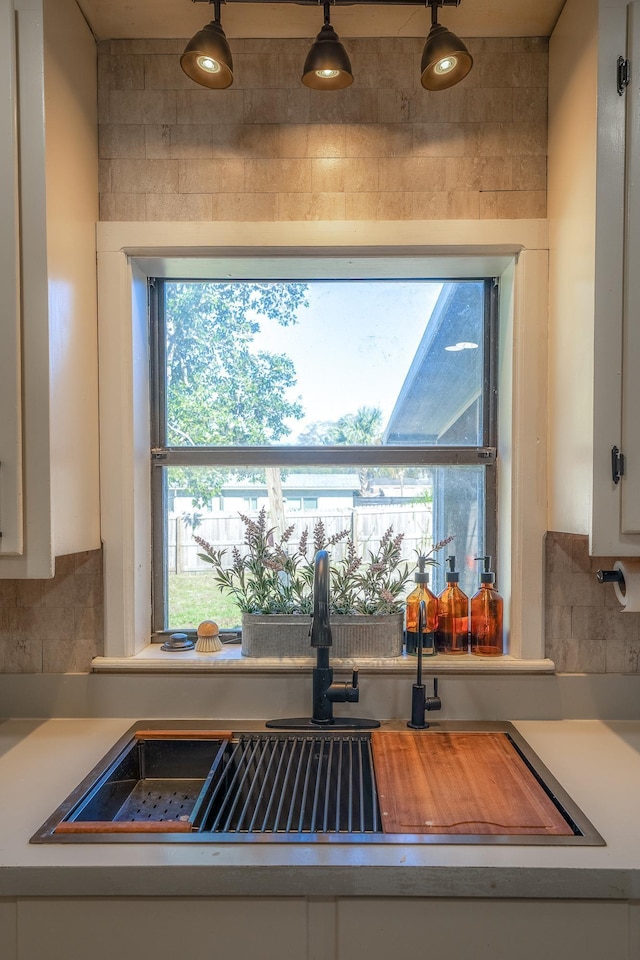 kitchen featuring light countertops, a healthy amount of sunlight, white cabinetry, and a sink