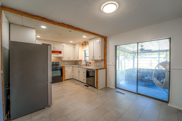 kitchen with tasteful backsplash, light countertops, black appliances, white cabinetry, and a sink