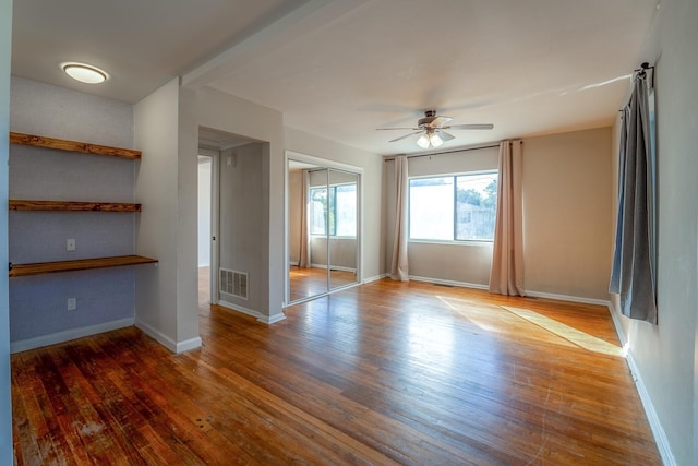 spare room with hardwood / wood-style flooring, baseboards, visible vents, and ceiling fan