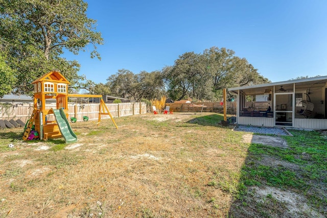 view of yard with a sunroom, a fenced backyard, and a playground