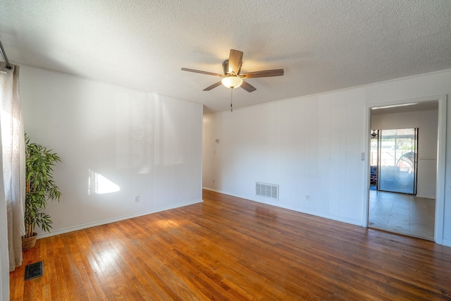 empty room with visible vents, ceiling fan, a textured ceiling, and hardwood / wood-style flooring