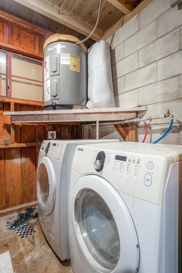 washroom featuring concrete block wall, laundry area, washing machine and dryer, and water heater