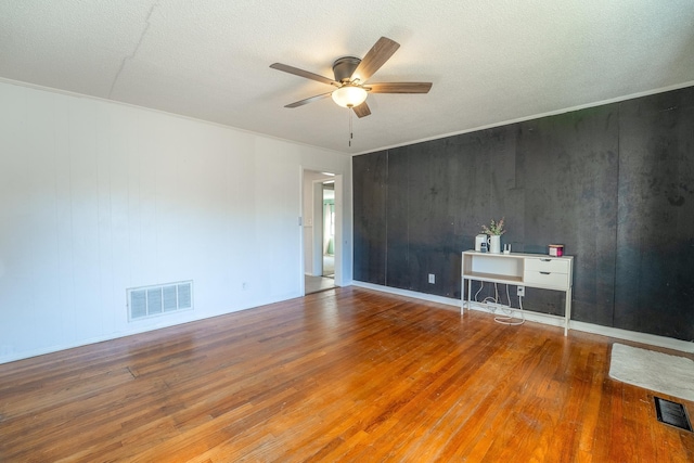 empty room featuring visible vents, ceiling fan, and wood finished floors