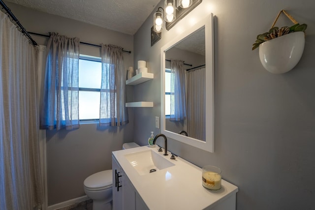 bathroom featuring a textured ceiling, toilet, vanity, and baseboards