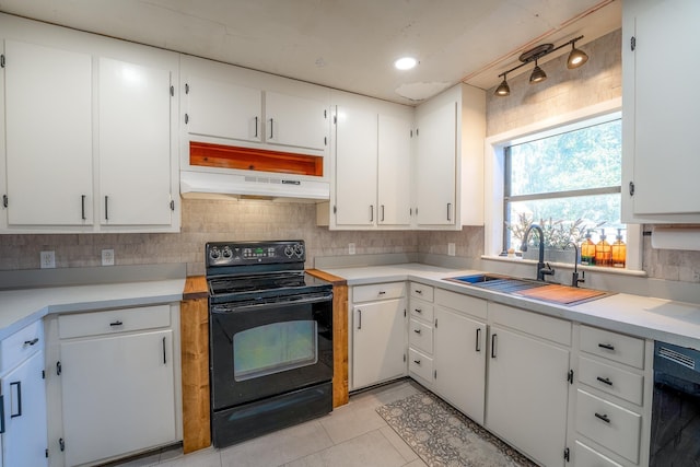 kitchen featuring under cabinet range hood, a sink, white cabinetry, backsplash, and black appliances