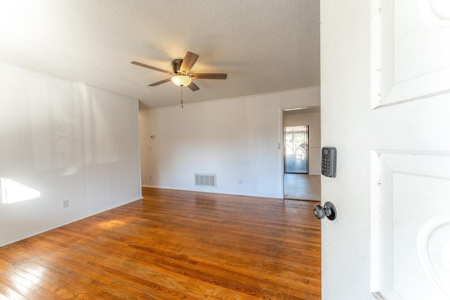 spare room featuring a ceiling fan, visible vents, a textured ceiling, and hardwood / wood-style flooring