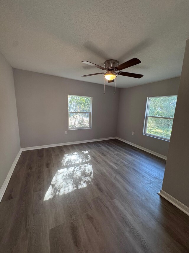 empty room with a textured ceiling, ceiling fan, and dark wood-type flooring