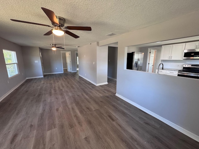 unfurnished living room with a textured ceiling, dark hardwood / wood-style flooring, ceiling fan, and sink