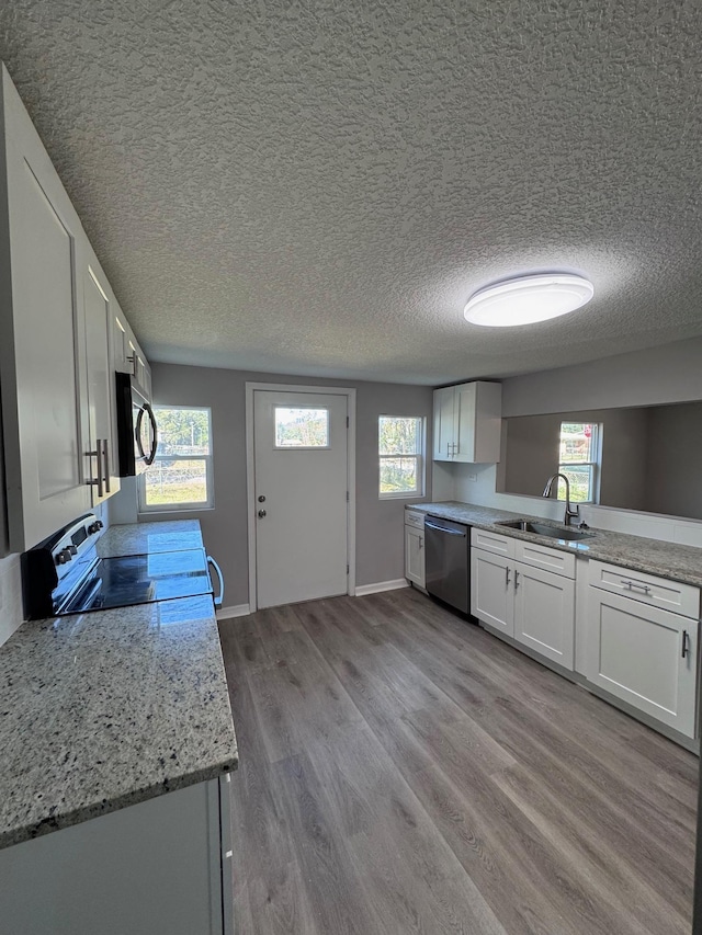 kitchen with a wealth of natural light, sink, white cabinets, and appliances with stainless steel finishes