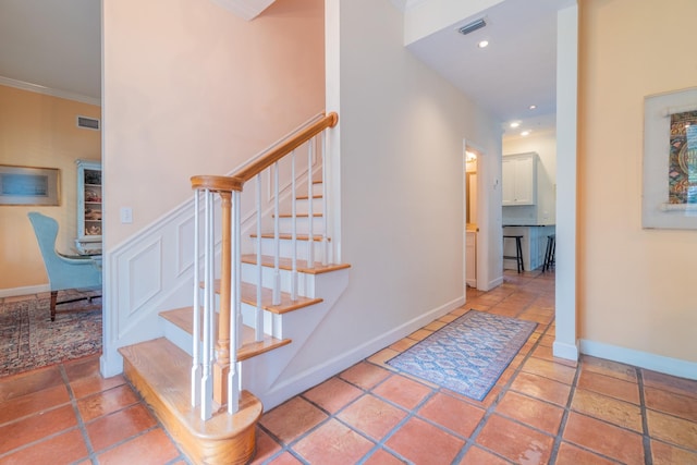 stairs featuring tile patterned floors and ornamental molding