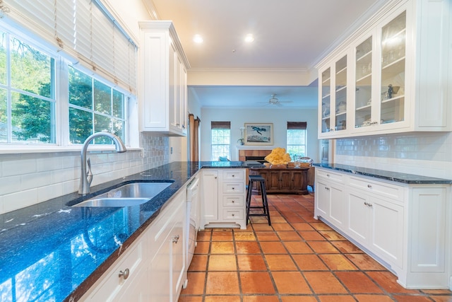 kitchen with backsplash, white cabinetry, crown molding, and sink