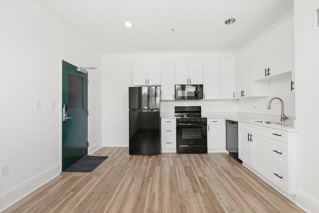 kitchen featuring light countertops, a sink, light wood finished floors, and black appliances