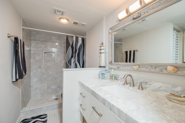 bathroom featuring visible vents, a tile shower, and vanity