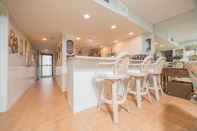 kitchen featuring light tile patterned floors, a wainscoted wall, recessed lighting, and white cabinetry