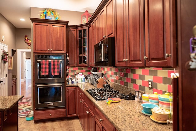 kitchen featuring glass insert cabinets, light stone countertops, recessed lighting, stainless steel appliances, and decorative backsplash