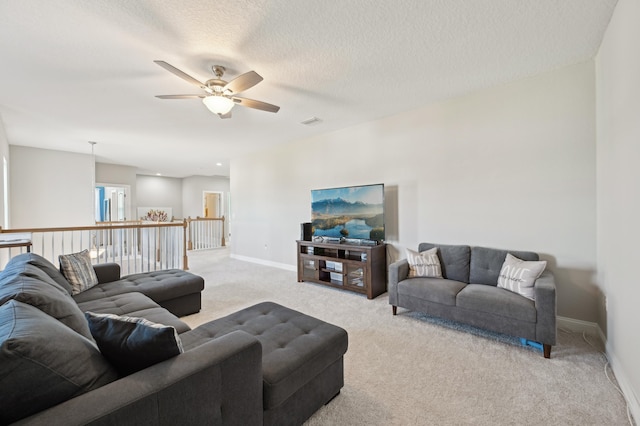 living room featuring ceiling fan, light colored carpet, and a textured ceiling