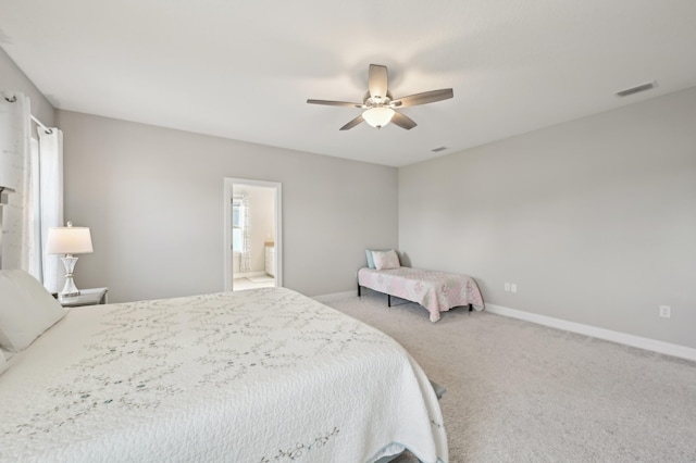 carpeted bedroom with multiple windows, ceiling fan, and ensuite bath