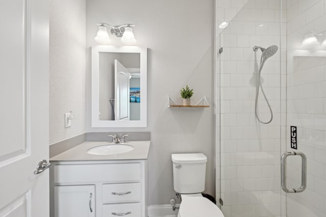 bathroom featuring vanity, a shower with shower door, and toilet