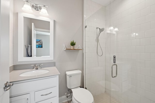 bathroom featuring a shower with door, vanity, and toilet