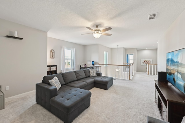 carpeted living room featuring ceiling fan and a textured ceiling