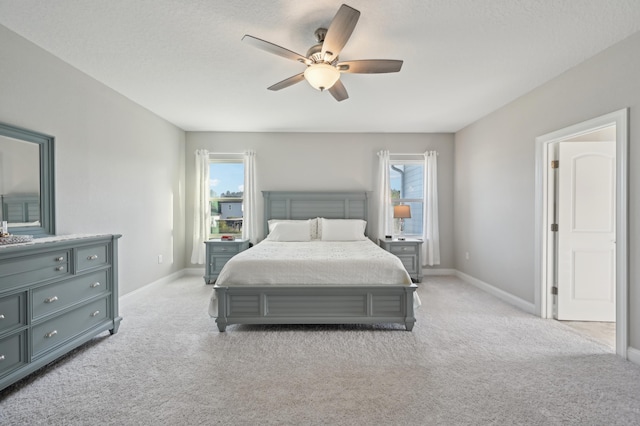 bedroom featuring ceiling fan, light colored carpet, and a textured ceiling