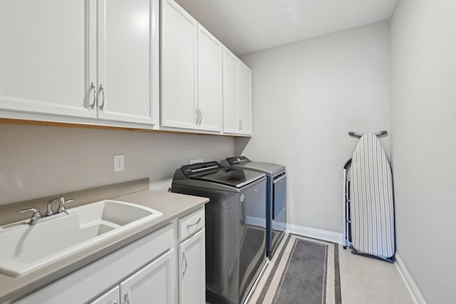 clothes washing area featuring sink, cabinets, and washer and dryer