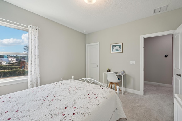 bedroom featuring light colored carpet and a textured ceiling