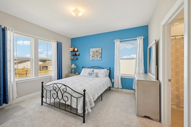 bedroom featuring multiple windows, light carpet, and a textured ceiling