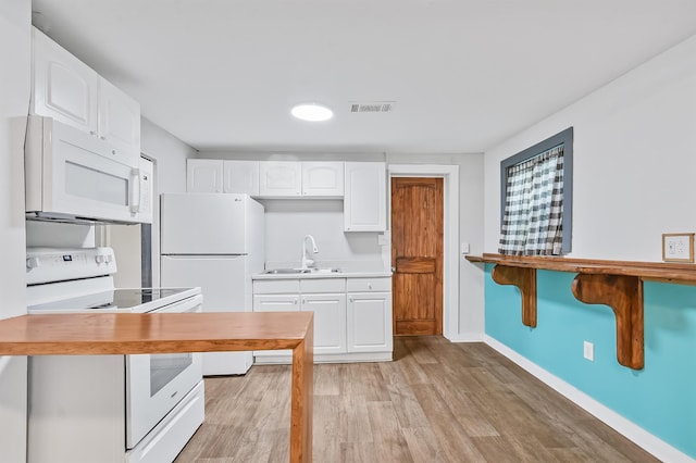kitchen with white appliances, a sink, light wood-style floors, white cabinets, and baseboards