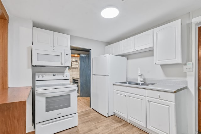 kitchen with white appliances, a sink, white cabinetry, and light countertops
