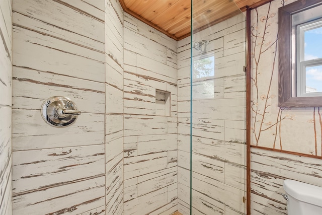 bathroom with wooden ceiling, wooden walls, tiled shower, and toilet