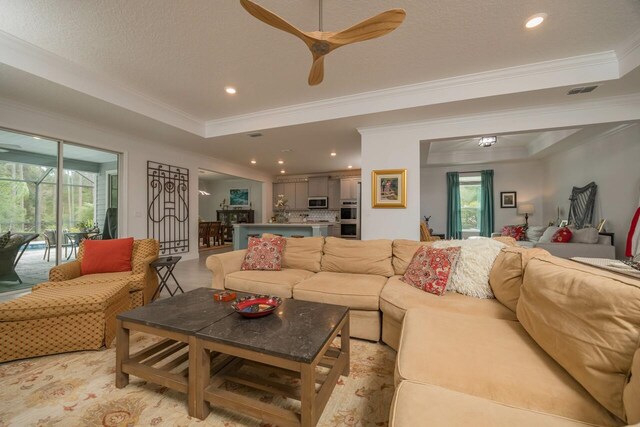 living room featuring crown molding, a tray ceiling, and a textured ceiling