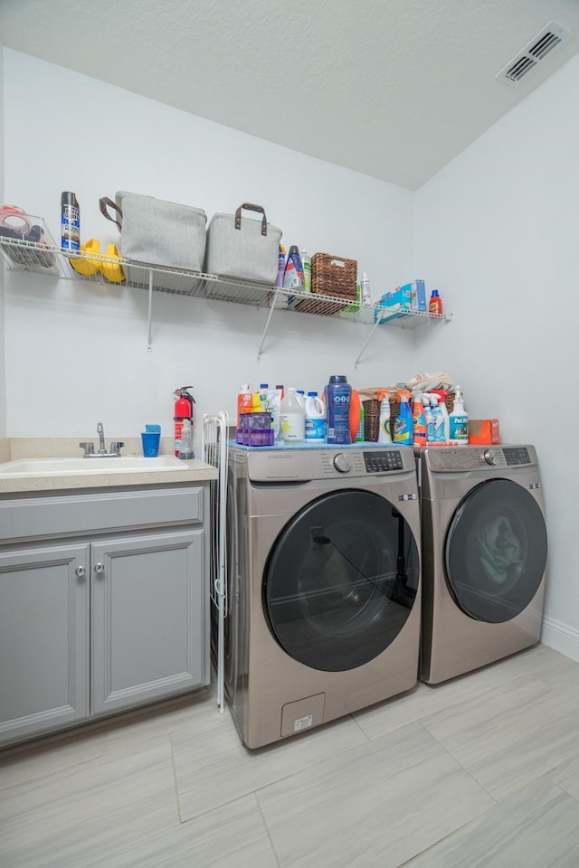 laundry room with cabinets, sink, and washer and dryer