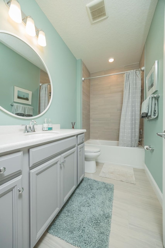 full bathroom featuring vanity, a textured ceiling, shower / bath combo, and toilet