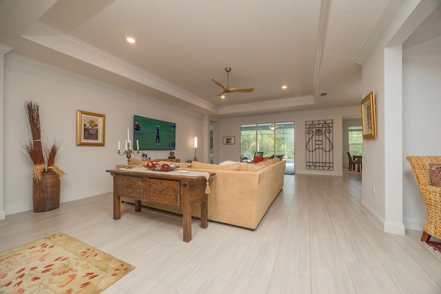 living room with ceiling fan, ornamental molding, and a raised ceiling