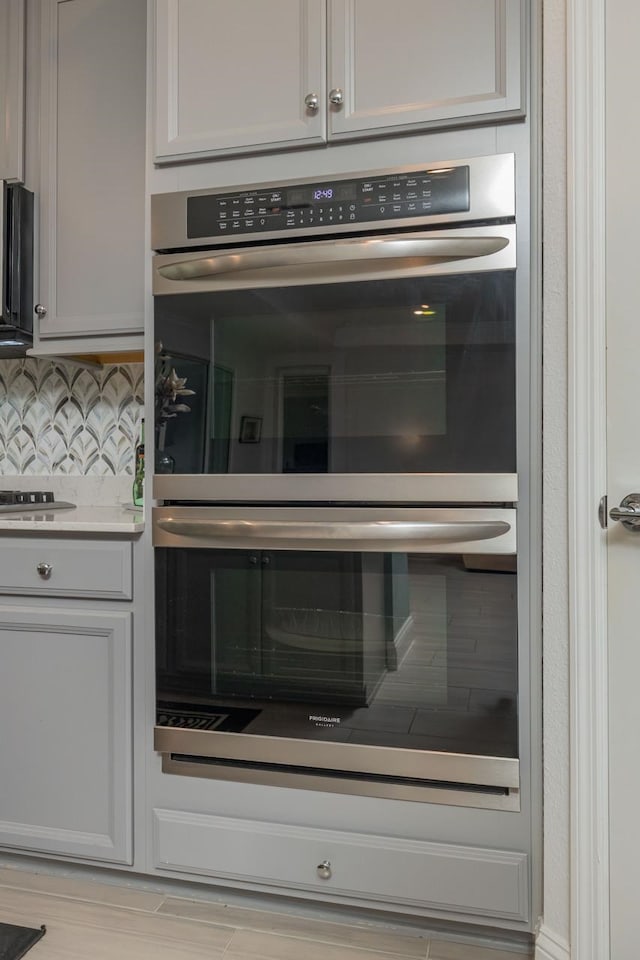 interior details with gas cooktop, double oven, and decorative backsplash