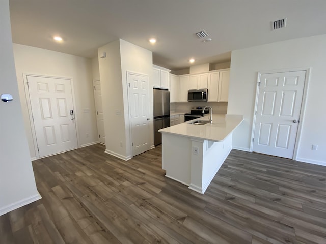 kitchen featuring white cabinetry, dark hardwood / wood-style floors, kitchen peninsula, and appliances with stainless steel finishes