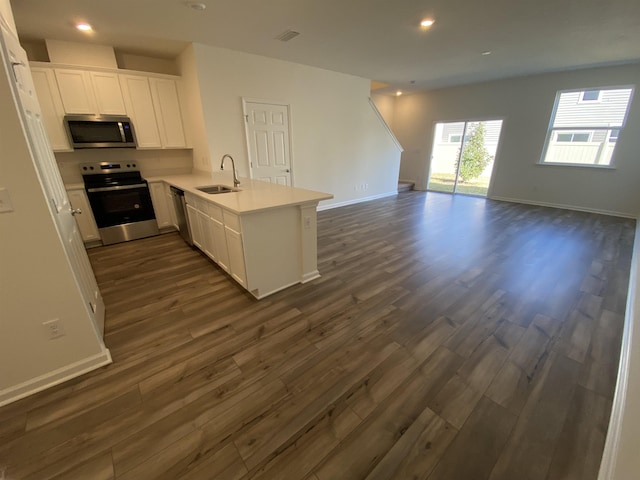 kitchen with kitchen peninsula, dark hardwood / wood-style flooring, stainless steel appliances, sink, and white cabinets