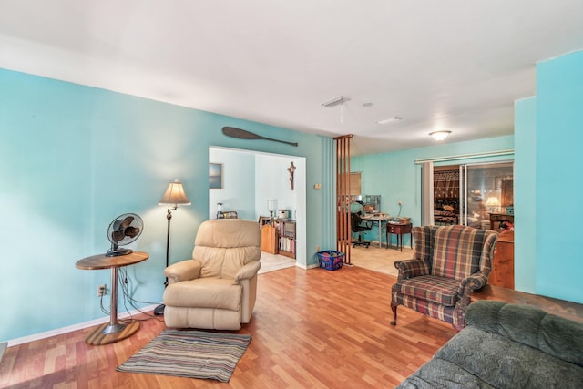 living room with light wood-type flooring, visible vents, and baseboards