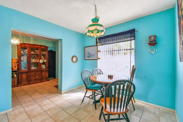 dining space with a textured ceiling, baseboards, and light tile patterned floors