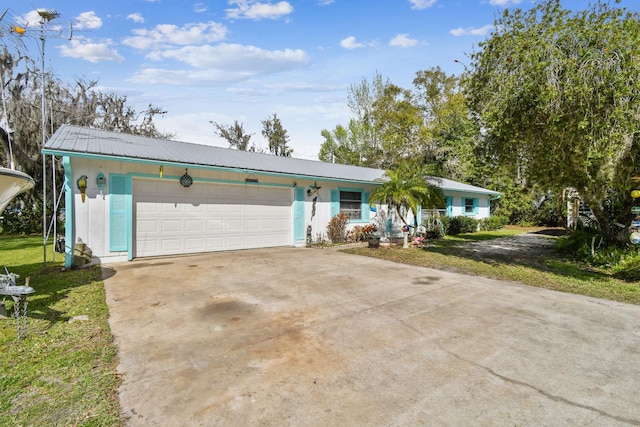 single story home featuring a garage, metal roof, and concrete driveway